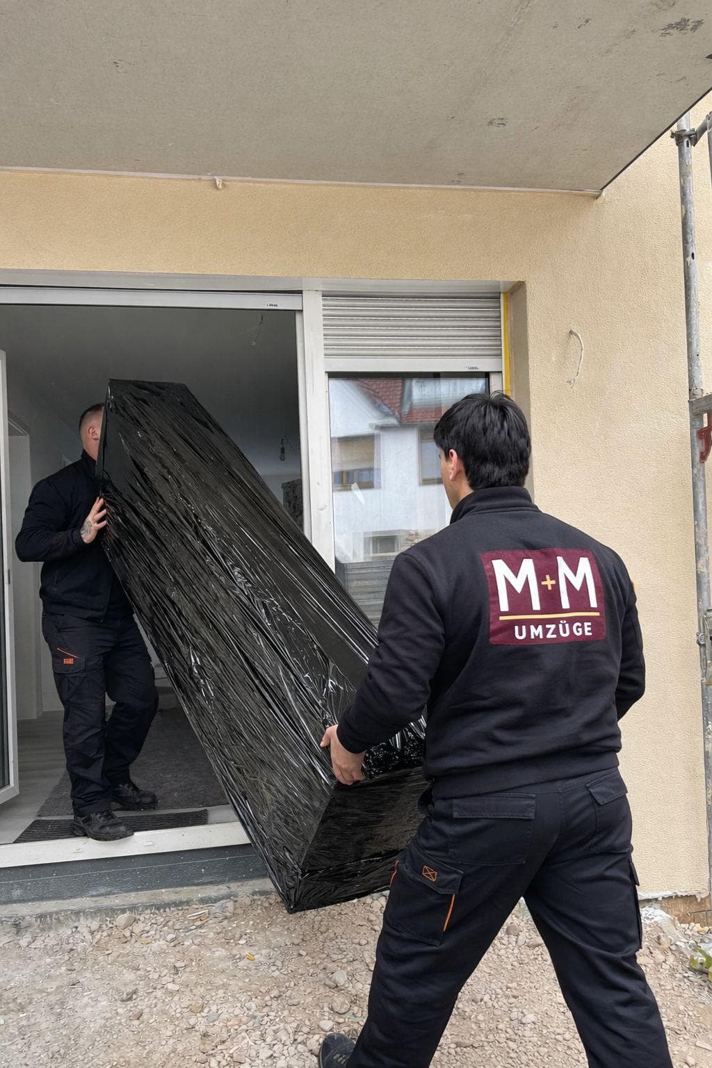 M+M Umzüge Team trägt verpackte Möbel ins neue Zuhause